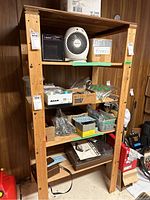 Front view of wooden shelving unit showing four shelves and some miscellaneous contents temporarily placed on it