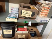 Shelf with labeled boxes: Binder clips (Staples medium binder clips), envelopes, box of staples, page protectors, Royal crosscut shredder LR14MX, box with folders 8½ x 11 inches, index card holders, calculator.