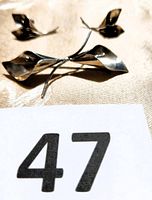 Photo of the sterling silver double Calla Lily brooch showing two flowers with curved petals and stems on a fabric background.