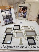 Full view of all frames in the lot: large wooden tree frame with photo openings, Lenox silver frame in original packaging, and two mahogany collage frames in original boxes.