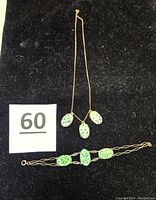 Full view of the necklace and bracelet laid out on a black surface with size reference and lot number