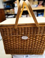 Front angle view of large rectangular wicker basket showing hinged lid and two wooden picnic handles, with Country Door charm on front.