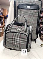 Front view of both luggage pieces showing the large suitcase at back and smaller carry-on in front, plaid pattern with black trim and handles visible