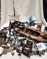 Photo of Mega Bloks Dragons Krystal Wars Man O War Ship partially assembled with scattered pieces, figures, and a large blue dragon figure in the background.