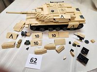 Assembled tank body with turret removed, multiple loose parts spread around it including wheels and blocks.