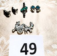 Group photo of the jewelry lot showing five pieces: two pairs of earrings, two pins including the donkey and cart pin, and a turquoise stone pin, with lot number 49 card.