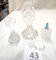 Group photo of all four vintage perfume bottles and stoppers on light background showing detailed shapes and designs.
