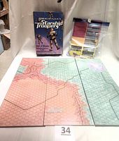 Folded game board with hex grid terrain, open box with original game components wrapped in plastic bags.