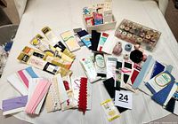 Overview of all sewing supplies including bindings, threads, zippers, buttons, and snaps laid out on a white background.