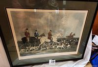Large framed print showing riders on horseback with a pack of stag hounds in a hunting scene, titled at the bottom.