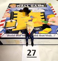 Photo of the Donald Trump figure standing on the game box showing the yellow blocks inside.