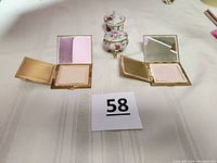 Two vintage mother of pearl compact cases open showing original puffs and mirrors