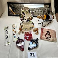 Full overview of the wine accessories lot including framed mirror, candle shade and plate set, wire bottle holder, wine aerators, glass charms, wooden stoppers, and glass dish.