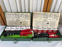 Wide angle of two Marson Klik Fast HP-2 riveters in green metal cases with multiple boxes of labeled rivets and instructional diagrams inside lid.