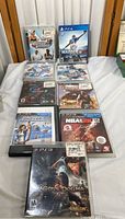 Photo showing nine PlayStation video game cases arranged on a surface, including Virtua Tennis 3, Madden NFL 21, Gran Turismo 5, Dragon's Dogma, Dark Souls II Remastered, NBA 2K13, Uncharted, and others.