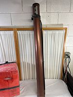 Full view of the Rod Caddy standing upright on a white surface against a background with wooden framed panels and electrical outlet.