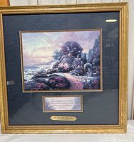 Framed print of Thomas Kinkade's "New Day Dawning," showing the entire piece including the frame and plaque beneath the image.