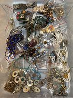 Overview of mixed vintage jewelry pieces arranged in multiple small plastic bags showing a wide assortment of bracelets, necklaces, beads, and brooches.