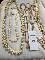 Photo showing entire collection of five sea shell necklaces and one pair of spherical bead earrings