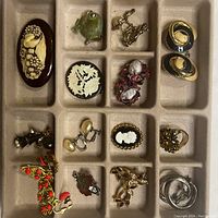 Top view of the velvet tray containing 14 vintage jewelry items including brooches and clip-on earrings of various designs and colors.