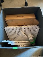 Storage bin containing stacked white triangular Nanoleaf panels, boxed power supply, and cable