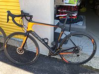 Side view of entire bicycle showing matte black and orange frame, wheels, and cockpit