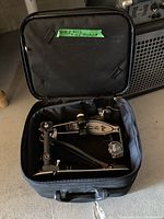 Soft-sided black storage bag unzipped showing DW pedals inside