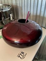 Front view of burgundy propane tank tongue drum with mallets inserted