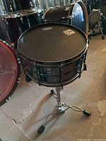 Front view showing Sonor snare drum mounted on stand, black shell and chrome hardware visible