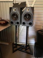 Front view of both black ADAM Audio A8X monitors on JamStands with four grey Auralex foam panels stacked on top.