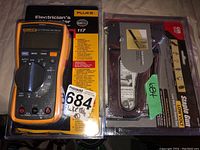Both Fluke multimeter and manual staple gun in original packaging