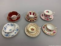 All six bone china porcelain teacup and saucer sets displayed together showing variety of colors and patterns.