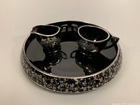 Photo of the round tray with attached creamer and sugar bowl, showing black amethyst glass and sterling silver floral decoration.