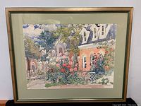 Full view of framed watercolor painting showing a cottage and garden scene.