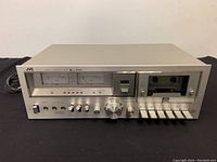 Front view of the JVC KD-55 stereo cassette deck showing control knobs, power switch, headphone and mic inputs, cassette chamber with tape inside, and VU meters.