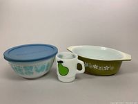 All items in the lot shown together: blue Amish Butterprint mixing bowl with lid, green Crazy Daisy Spring Blossom casserole, Fire-King pear mug.