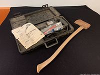 Sears Craftsman reciprocating saw, hard plastic carrying case, multi-page user manual, and old axe laid out on black cloth.