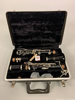 Wide photo showing the clarinet disassembled into three main parts in original black velvet-lined case with mouthpiece and small accessories.