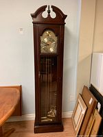 Front view of vintage HENTSCHLE Tempus Fugit grandfather clock showing clock face, pendulum, and cherrywood finish.