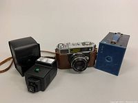 Photo showing Taron VL camera with leather case, Kodak Brownie #2 box camera, and Pentax AF200T flash.