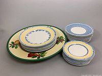 Stacked 6 dinner plates, 9 luncheon plates, 6 dessert plates on a table next to the large serving plate, showing the blue and yellow border pattern of the Casa Azul Limon design.