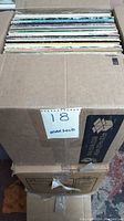 Box containing approximately 100 vinyl records in sleeves.