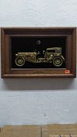 Front view of framed 3D metallic Bugatti Royale model on black velvet background in wooden frame.