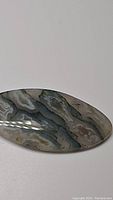 Close-up photo showing the natural moss agate cabochon with its unique organic patterns and smooth polished surface.
