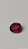 Close-up top view of oval cut natural ruby showing deep red color and polished surface.