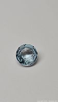 Front-facing clear image of the 1.43ct natural round sky blue topaz gemstone showing its color and internal clarity against a plain background.