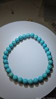 Photo of natural robin's egg blue turquoise round bead stretchy bracelet laid flat in circular shape on a light background, showing smooth uniform beads.