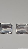 Two emerald cut rose quartz stones, light pink color, clear quality with minor inclusions.