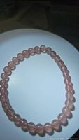 Photo showing round translucent baby pink strawberry quartz beads on an elastic bracelet.