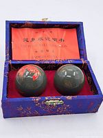 Two Chinese exercise balls in a fabric-covered box with an instruction sheet inside the lid.